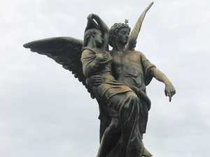 Sculpture of an angel carrying a young person while treading on a demon located in the Recoleta cemetery in Buenos Aires, Argentina.