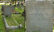 A granite headstone in the shade of a tree, surrounded by other gravestones